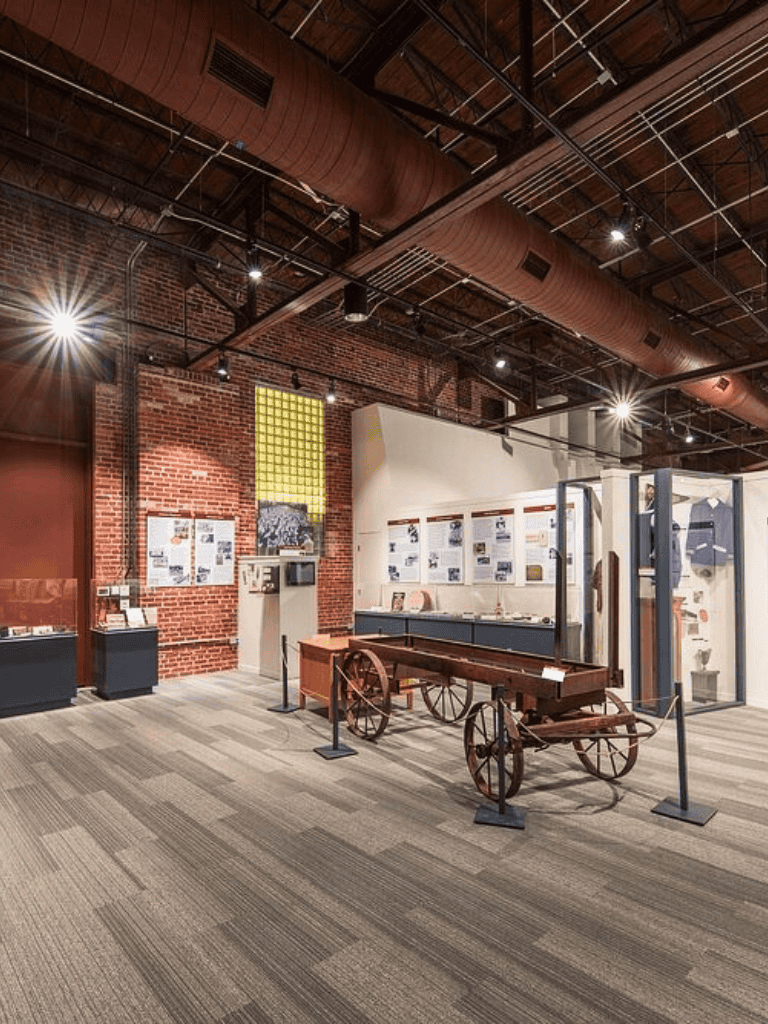 Vintage wooden cart display in modern industrial museum interior.