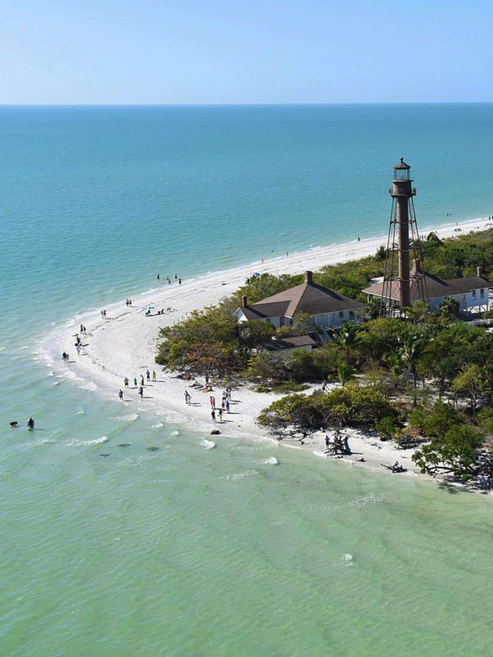 Lighthouse on beach at sunset, scenic coastal view, popular travel destination, scenic lighthouse photo, beach vacation spot for travelers.