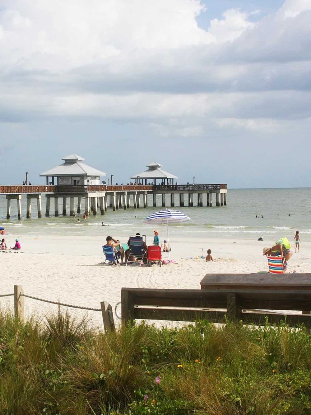 Beach pier with people relaxing and seaside scenery, perfect for vacation and travel keywords.