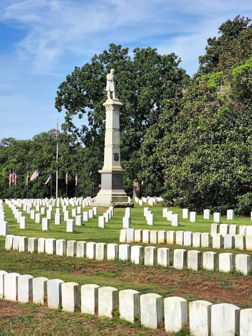 Veterans Memorial with statue and American flags, honoring fallen soldiers, outdoor historical site.