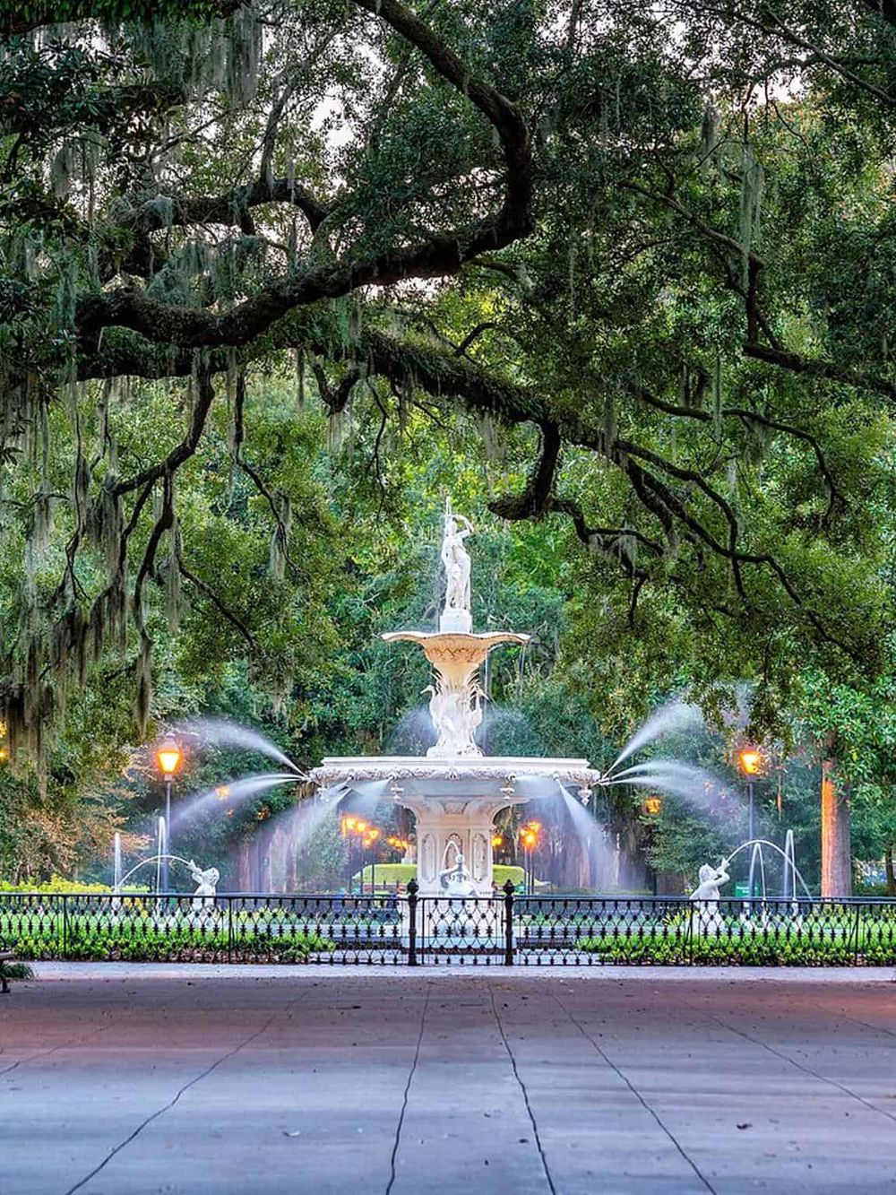 Lush green park with ornate fountain surrounded by trees, ideal for relaxing and outdoor activities.