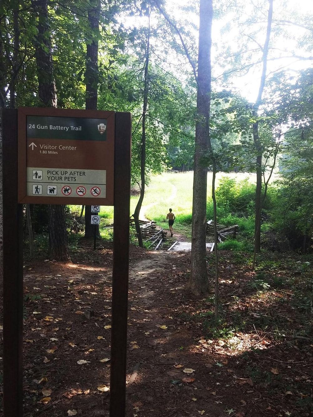 Quiet forest trail leading to visitor center at Gun Battery Trail with pet-friendly and accessible features.