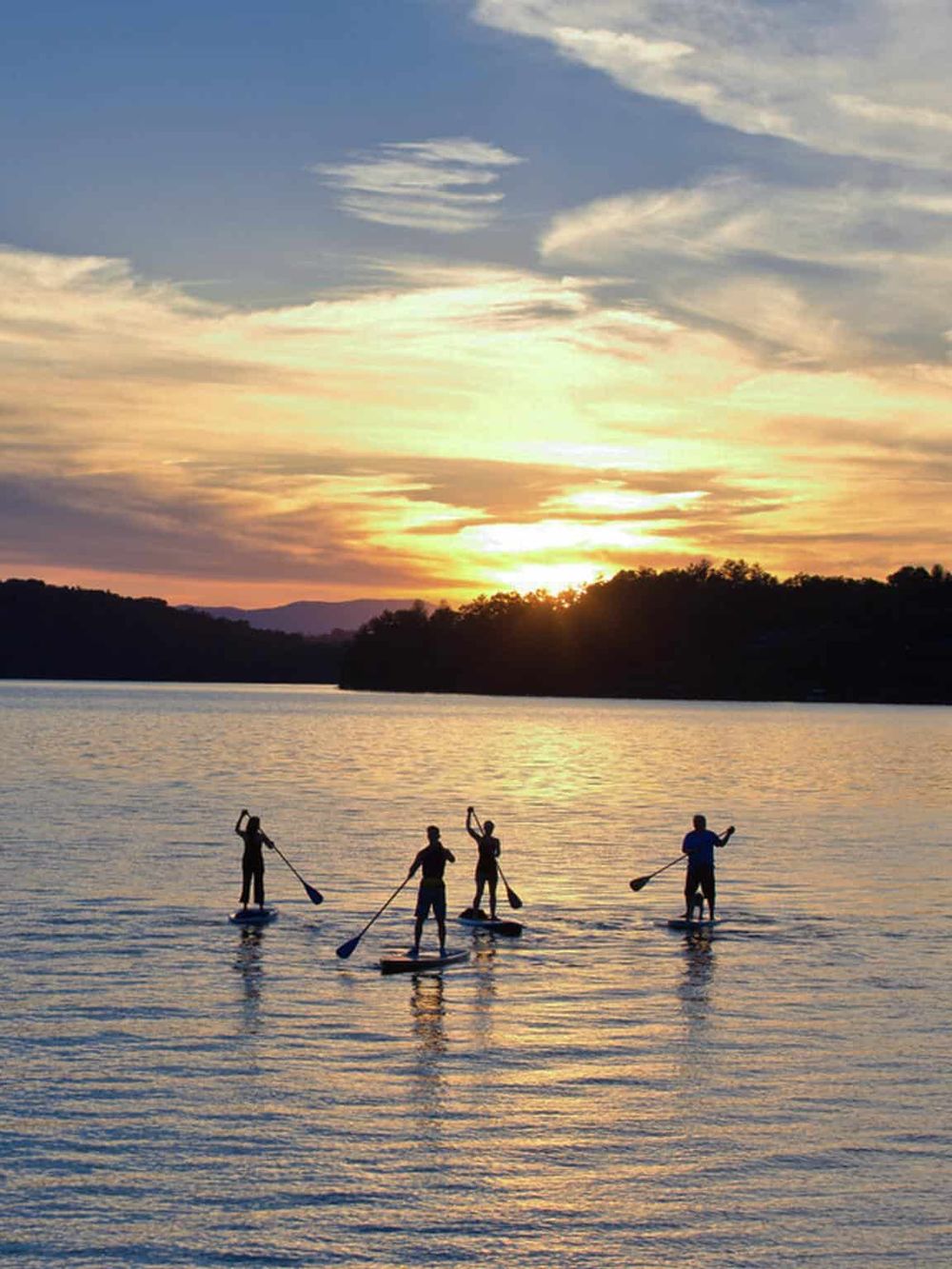 Paddleboarding at sunset over a calm lake, a perfect outdoor adventure and scenic escape.