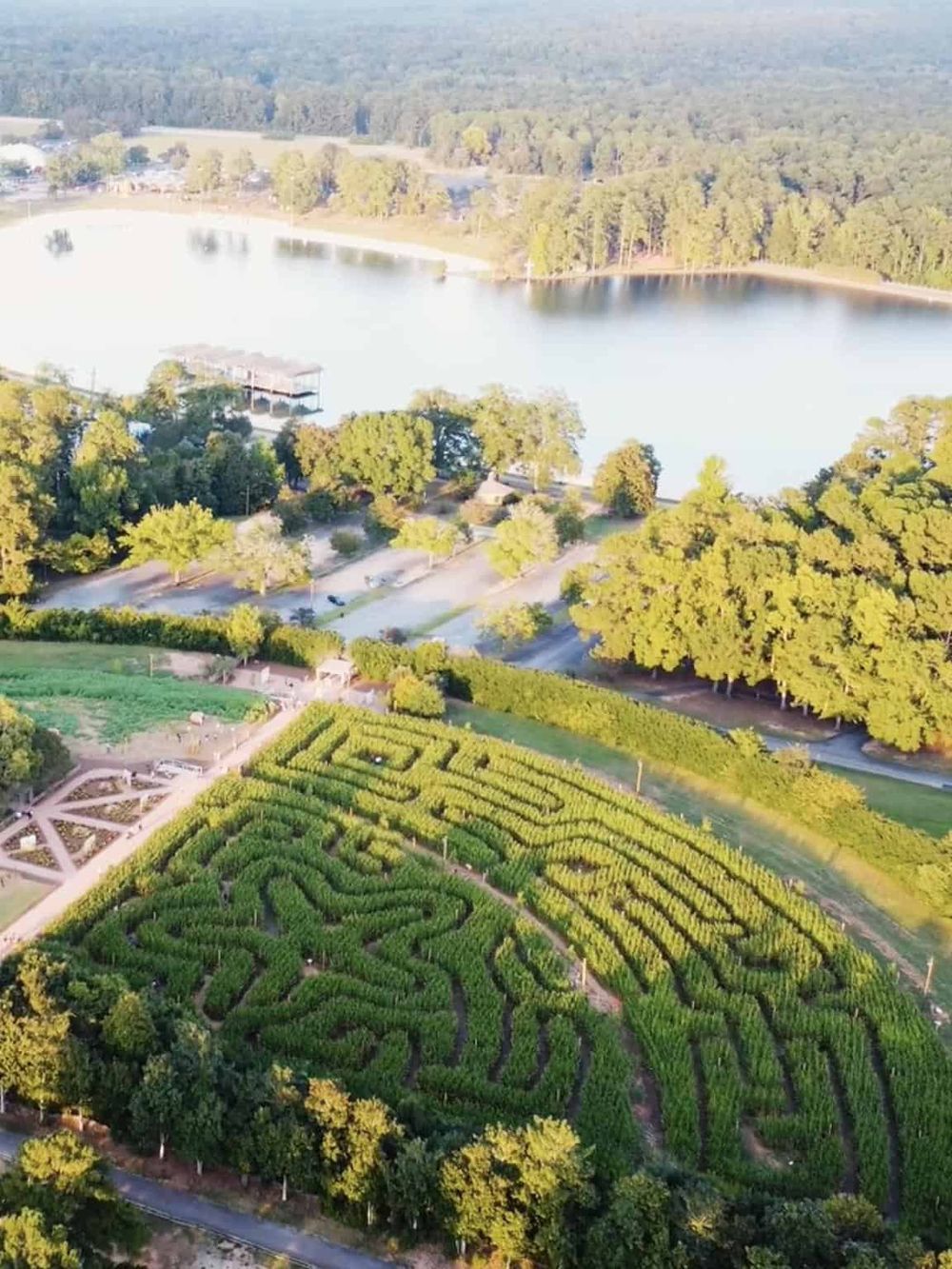 Aerial view of QuestForDirections park with maze, lake, and lush greenery, perfect for outdoor exploration and navigation.
