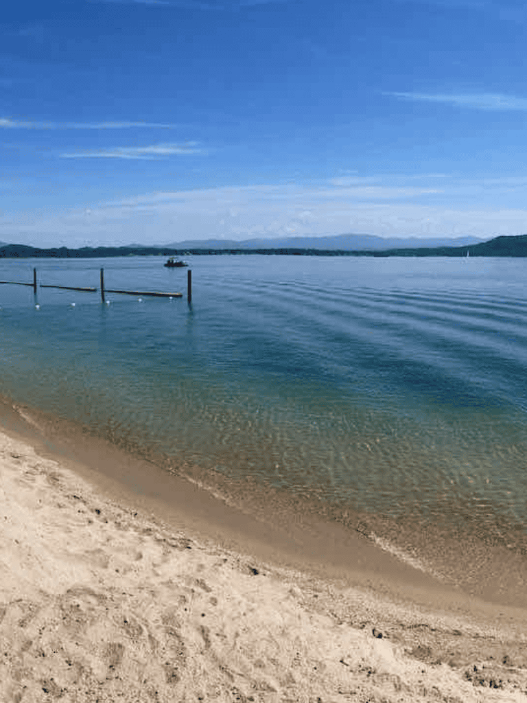 Tranquil lakeside scene with sandy beach and boat dock, perfect for outdoor adventures.