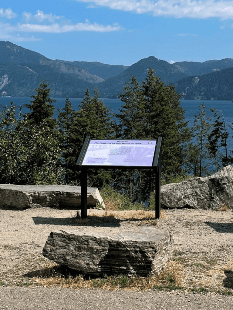 Scenic lakeside mountain view with interpretive trail sign at a nature park.