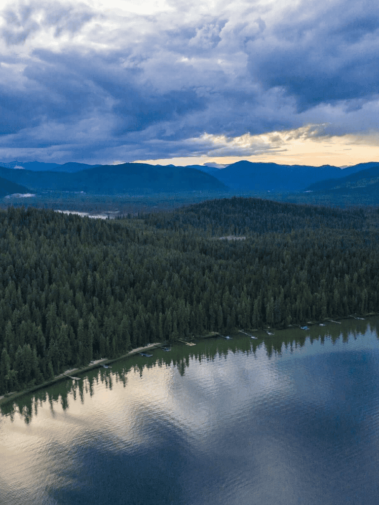 Serene mountain lake surrounded by lush forests with cloudy sky, ideal for outdoor adventures.