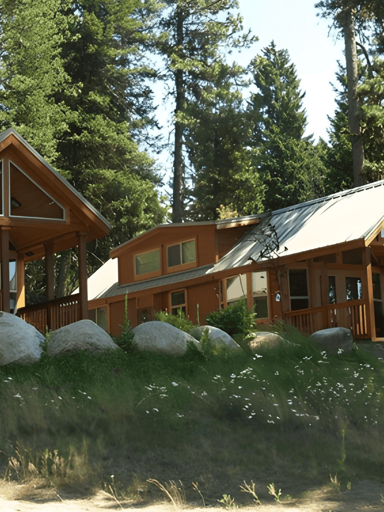 Cozy mountain cabin surrounded by tall pine trees and large rocks, ideal for outdoor adventure and nature retreats.