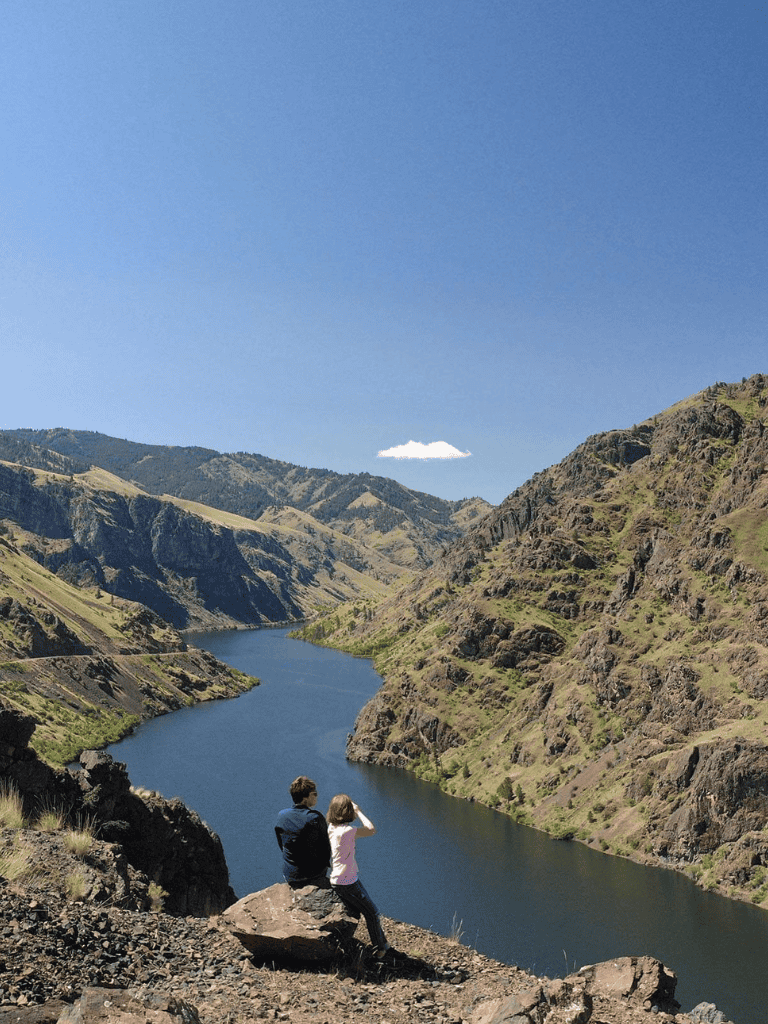 Breathtaking canyon scenery with two hikers overlooking a river and rugged mountains.
