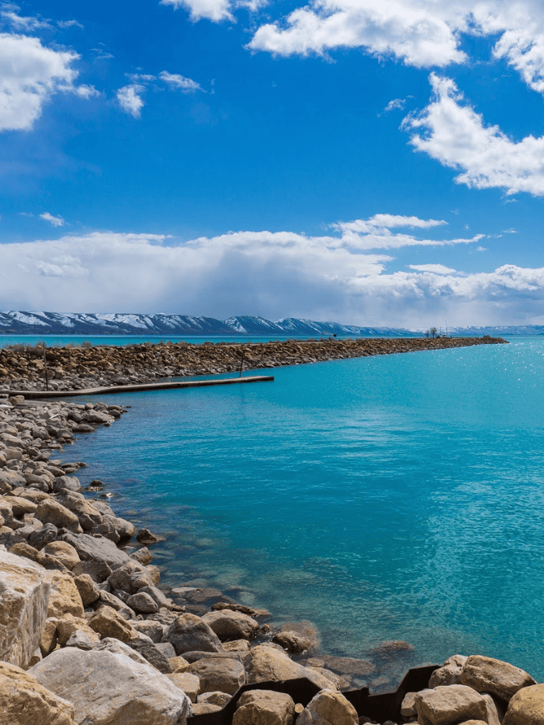 Stunning mountain and lake scenery with rocky shoreline and clear blue water in serene outdoor setting.