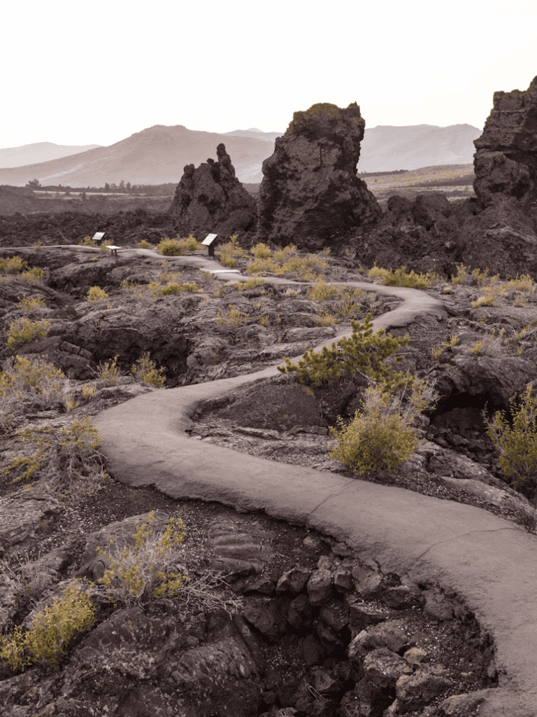 Winding trail in volcanic landscape with rock formations and sparse vegetation, QuestForDirections.