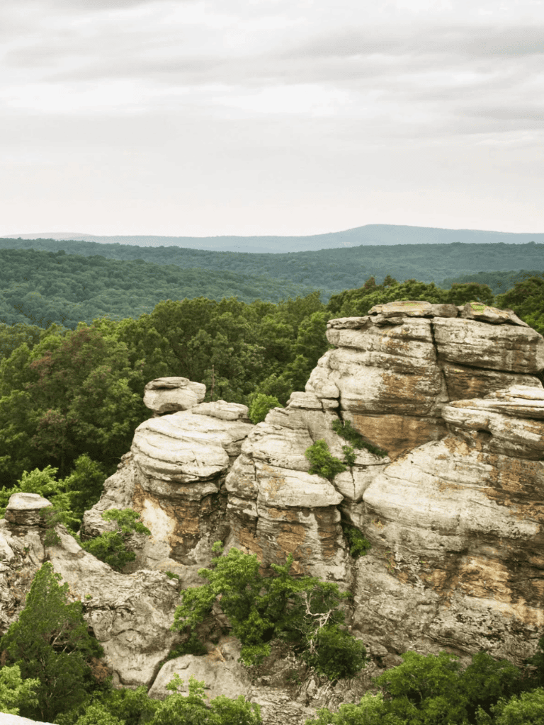 Rolling sandstone formations in lush green forest landscape, Missouri Ozarks, scenic outdoor exploration.