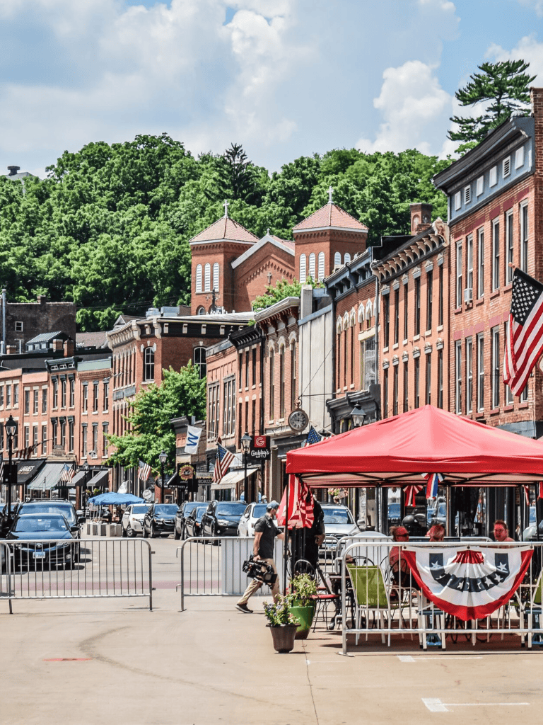 Historic downtown Main Street with vibrant shops, patriotic decor, and a lively outdoor cafe scene.