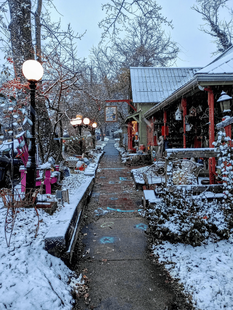 Cozy winter street scene with snow-covered shops, vintage decor, and charming lamps in a small town.