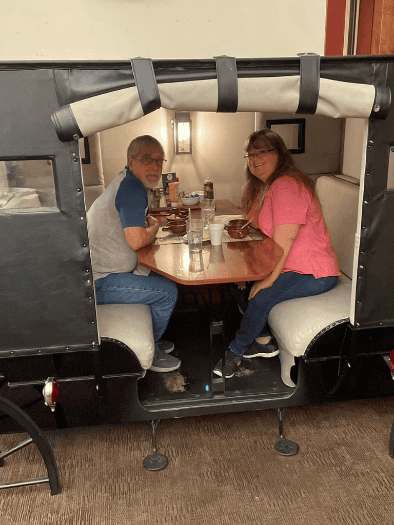 Enjoying a meal inside a unique, covered wagon-shaped booth at QuestForDirections restaurant.