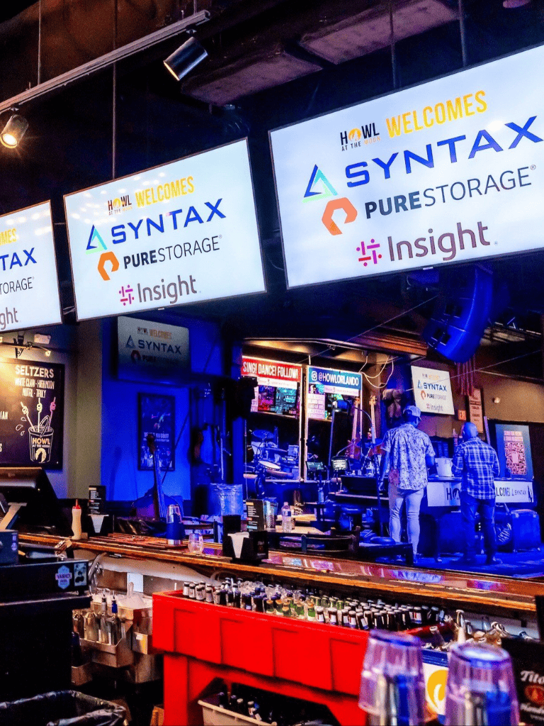 Creative digital signage display at Howl Orlando showcasing branding for Syntax, Pure Storage, and Insight.