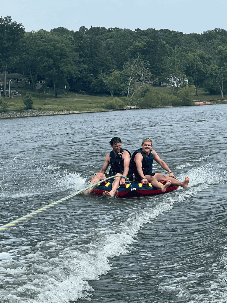 1. Two kids enjoying water tubing adventure on a lake near wooded shoreline.