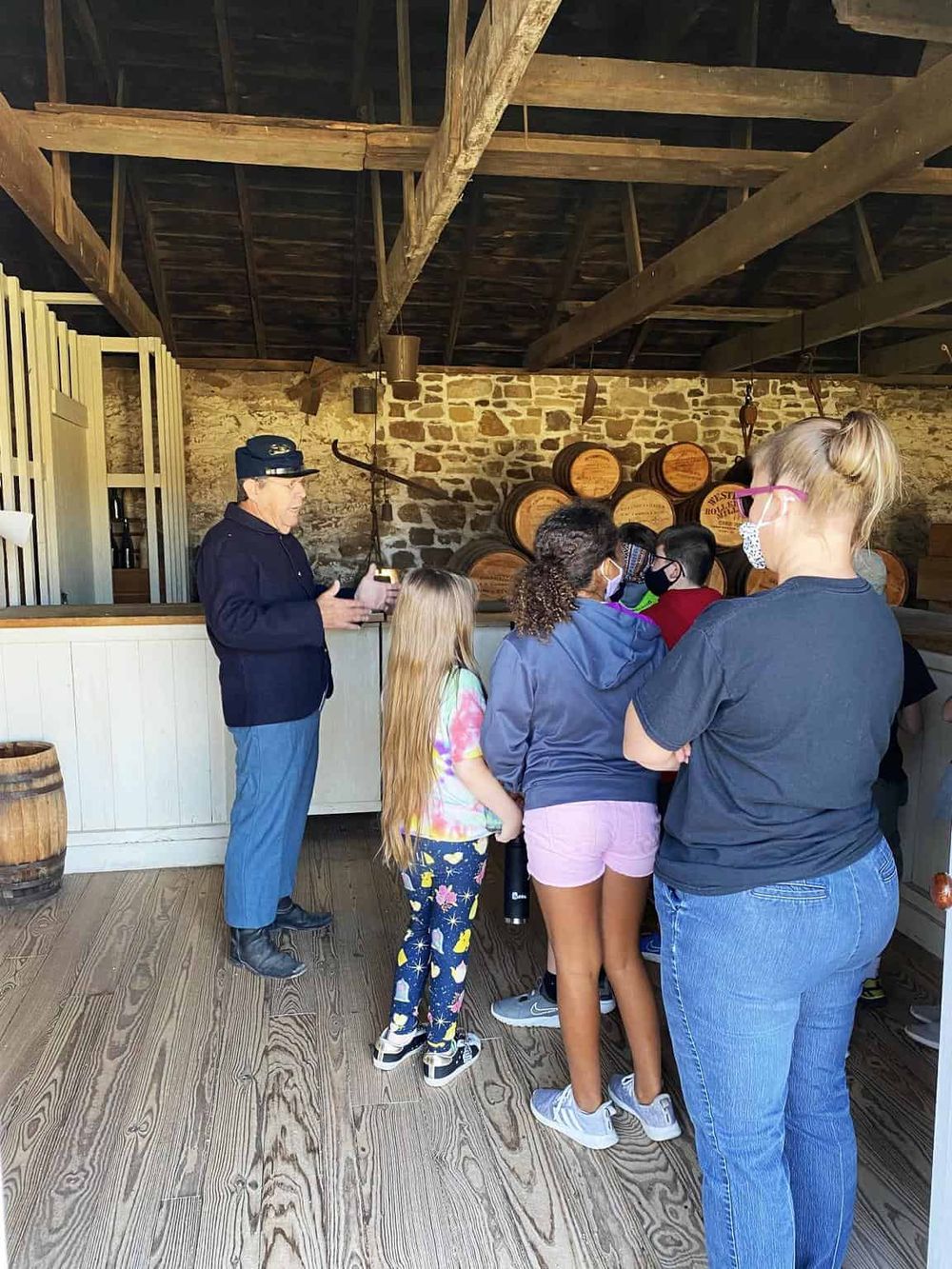 Guided whiskey tasting tour at QuestForDirections distillery, showcasing a group learning about whiskey barrels and production process.