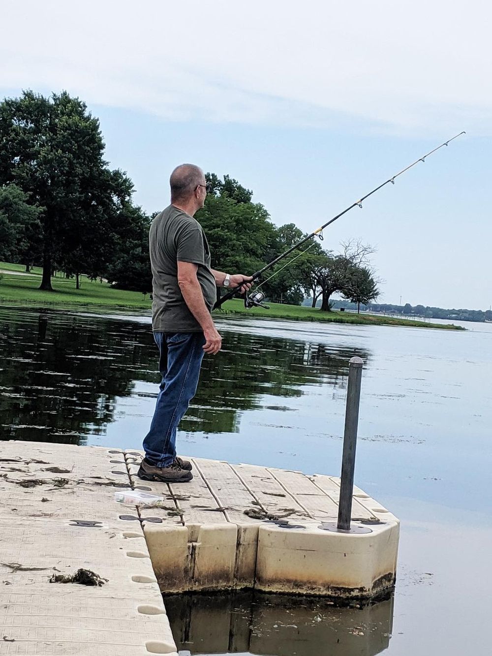 Someone fishing on a dock by a peaceful lake.