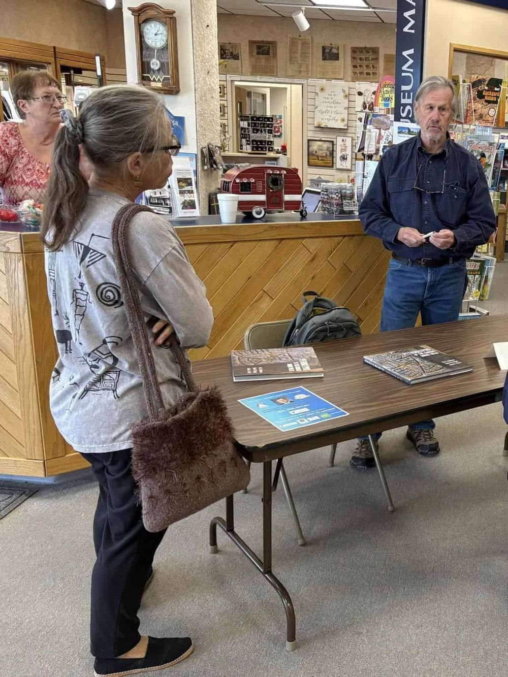 Informative visitor at museum information desk discussing directions and museum exhibits with staff.