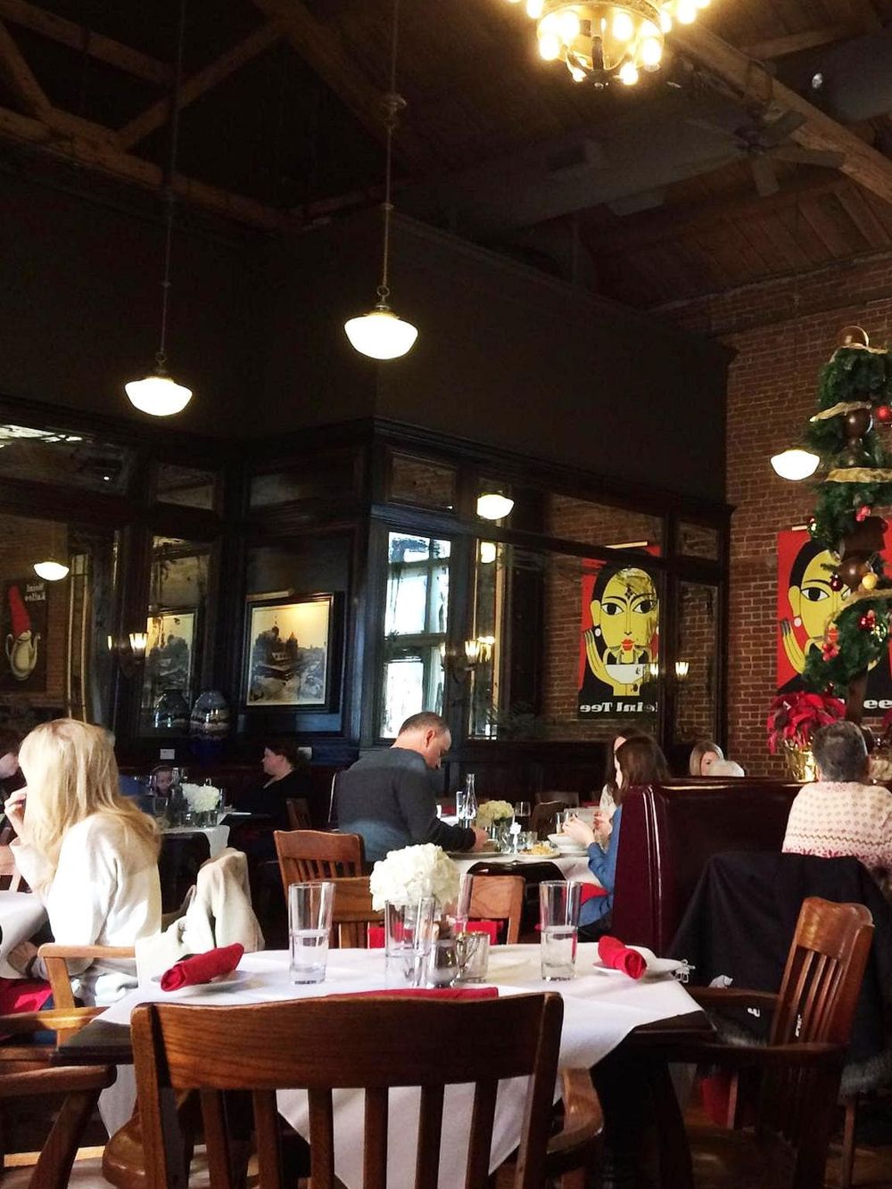 Elegant restaurant interior with brick walls, wooden furniture, and festive holiday decorations.