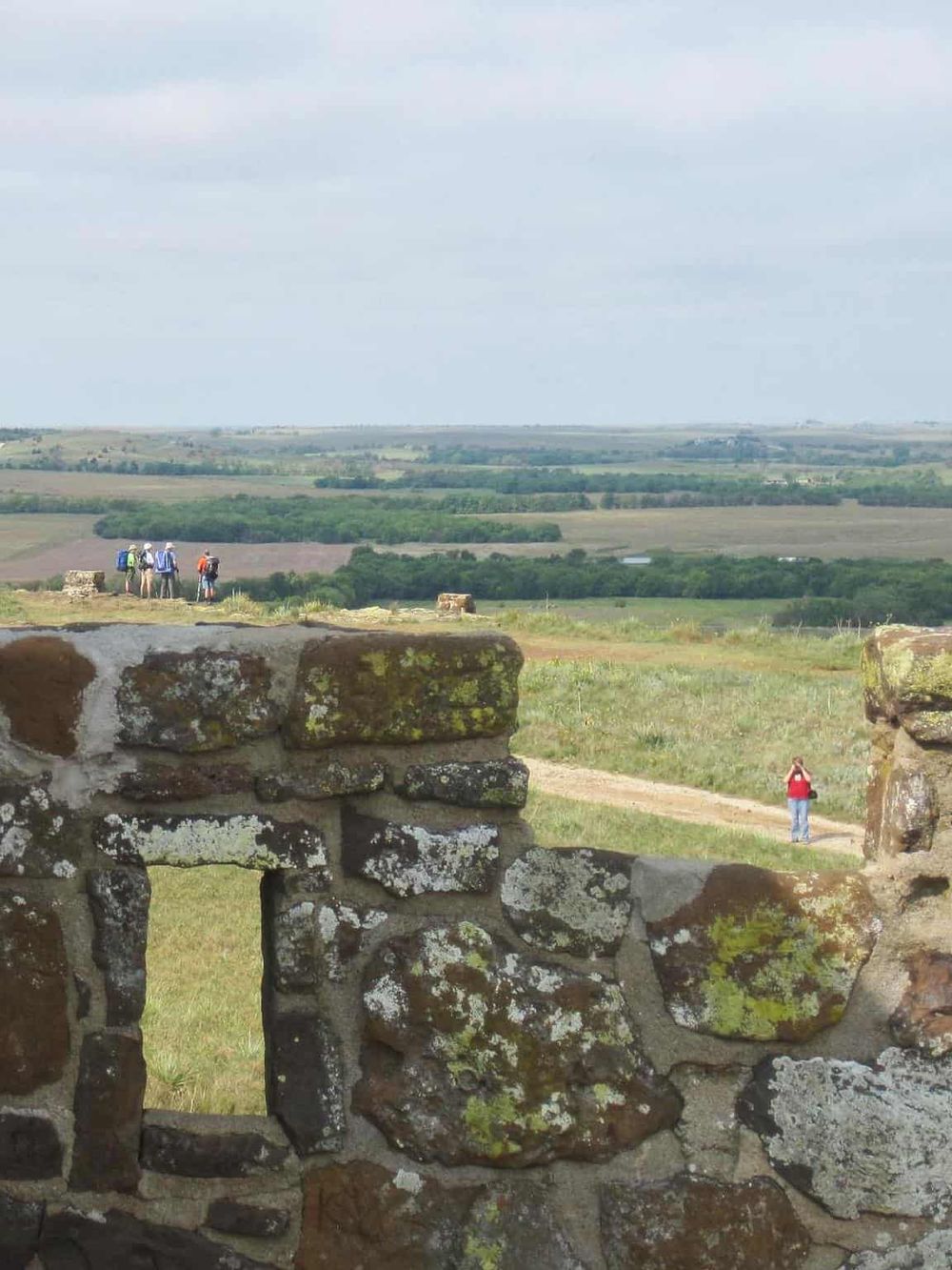 Scenic outdoor view from ancient ruins, countryside landscape, tourists exploring historical site, green rolling hills, travel adventure.