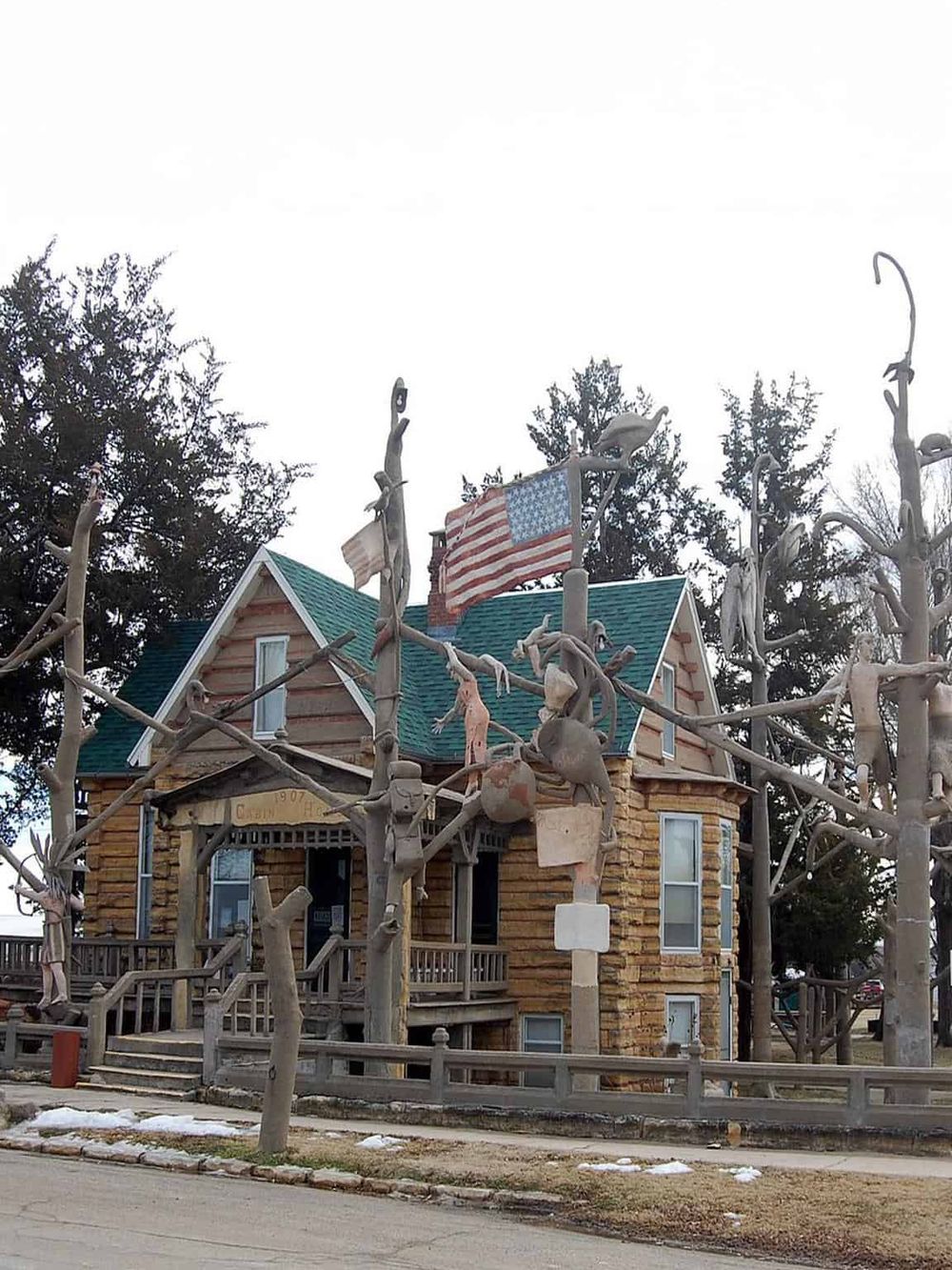 Colorful haunted house with skeletons and flags, showcasing outdoor Halloween decorations and spooky yard art.