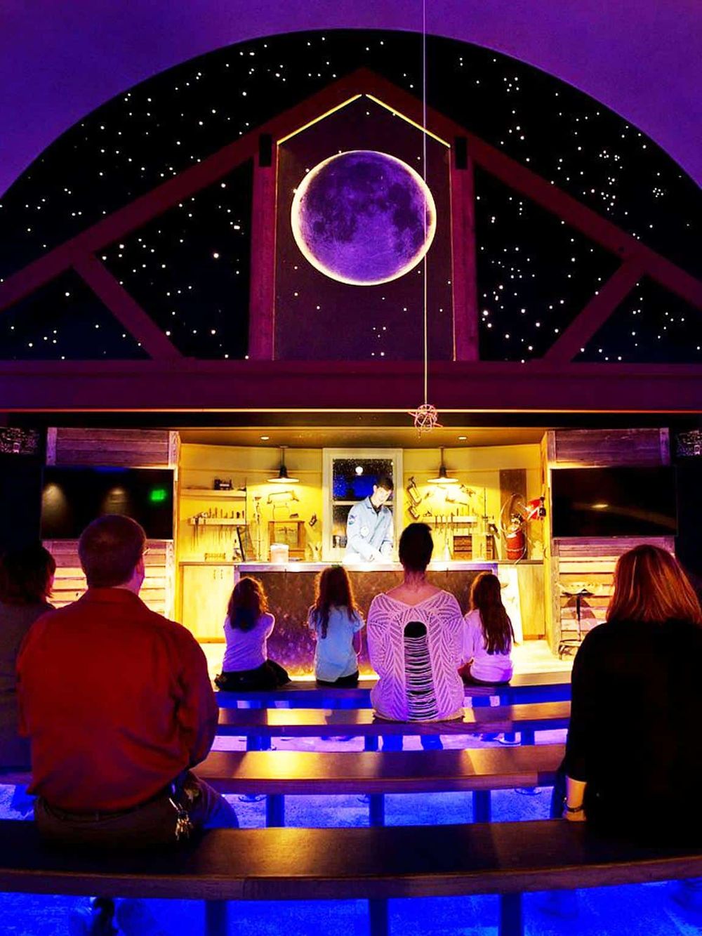 Stunning galaxy-themed performance space with viewers watching a science show under a starry sky.
