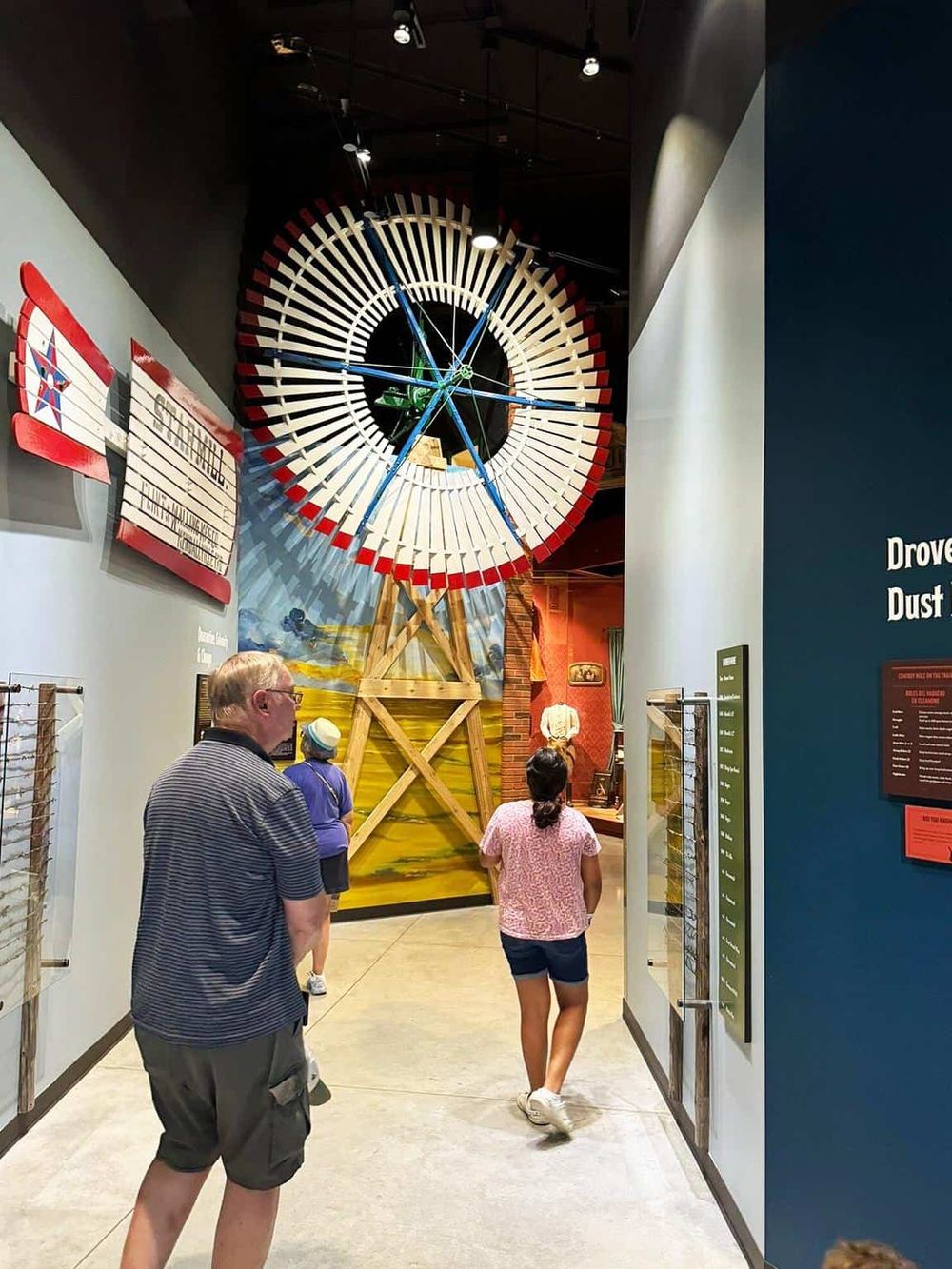 Colorful historical museum exhibit featuring a large wooden windmill model and visitors exploring the displays.