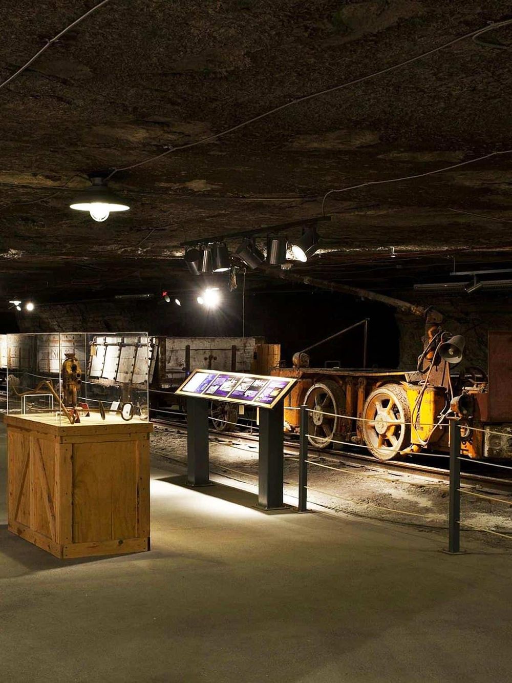 Vintage mine tunnel exhibit with mining equipment and informational signage.