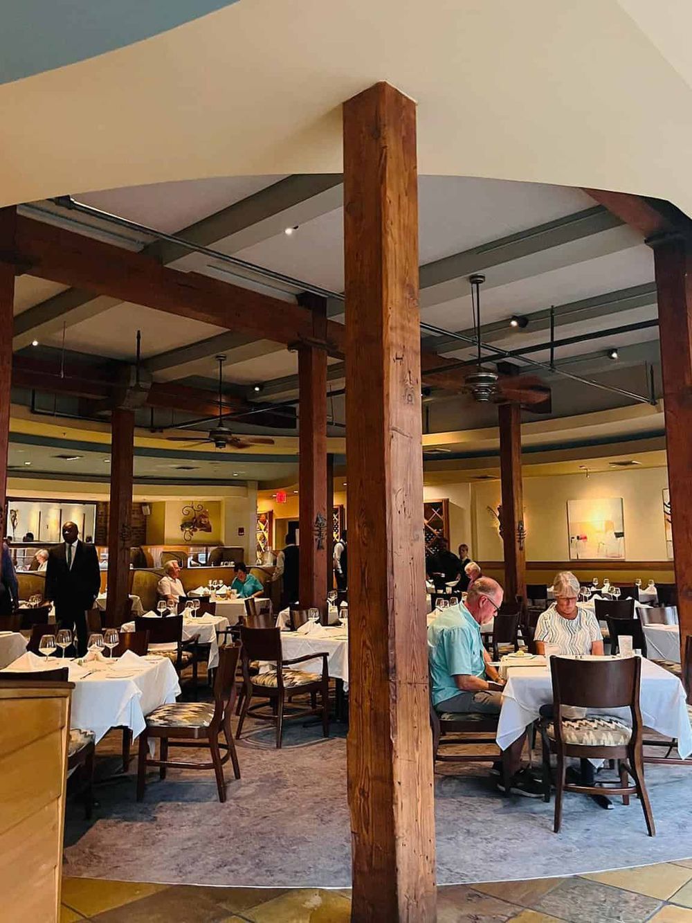 Elegant restaurant interior with wooden beams and white tablecloths, inviting for dining experiences.