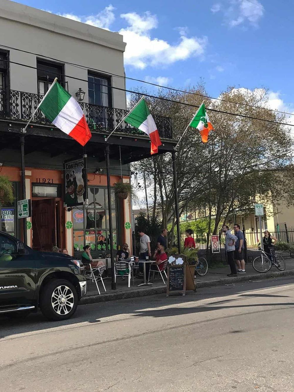 Traditional Italian restaurant with outdoor seating and Italian flags, featuring a lively sidewalk scene and city ambiance.