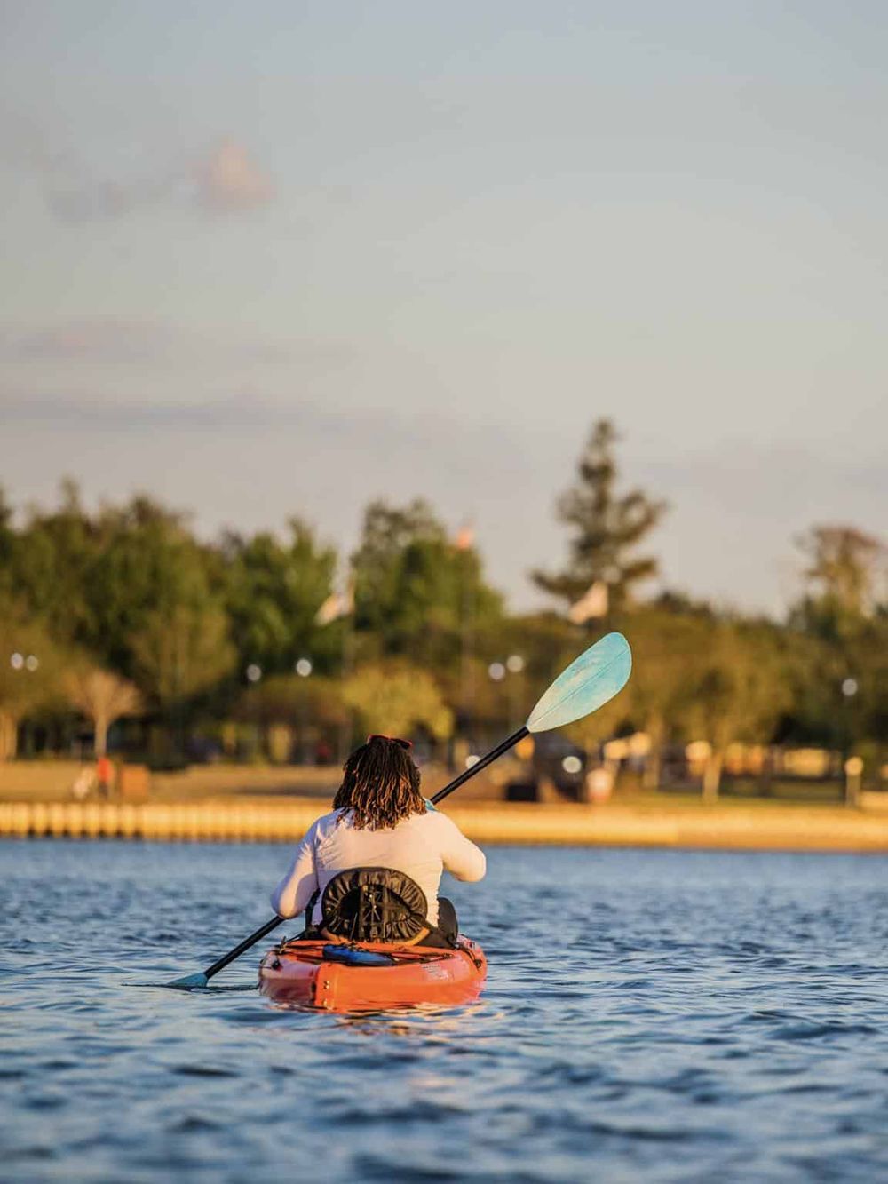 Serene kayaking on calm waters with a scenic park background, perfect for outdoor adventure and exploration.