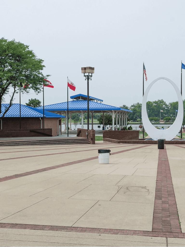 Empty park with flags, modern circular art sculpture, and pavilion at QuestForDirections site.