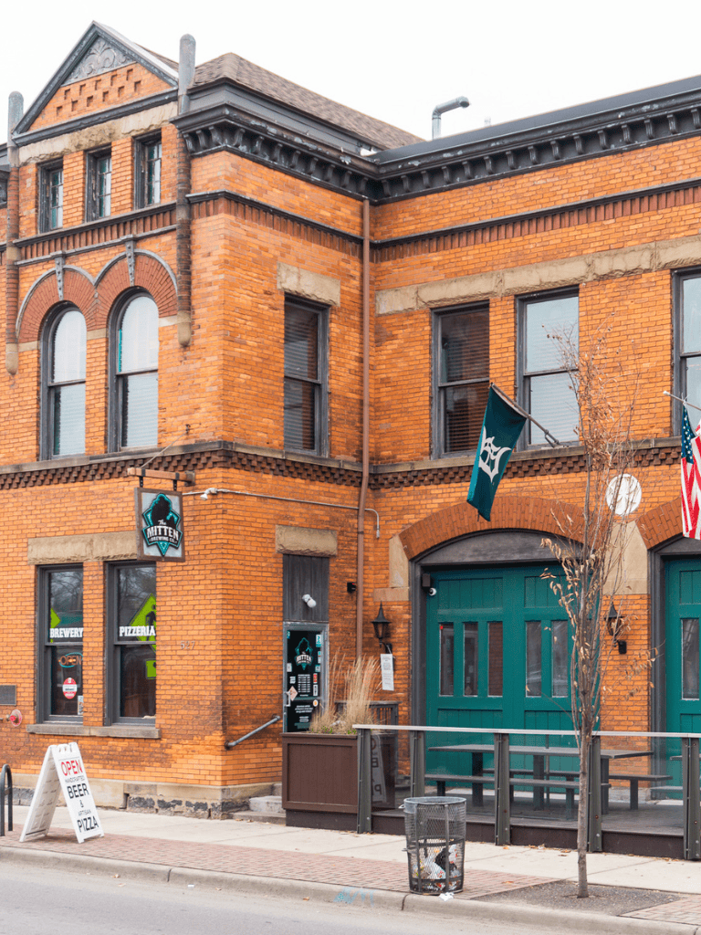 - Brick building with brewery and pizzeria signs, historic architecture, and flags.