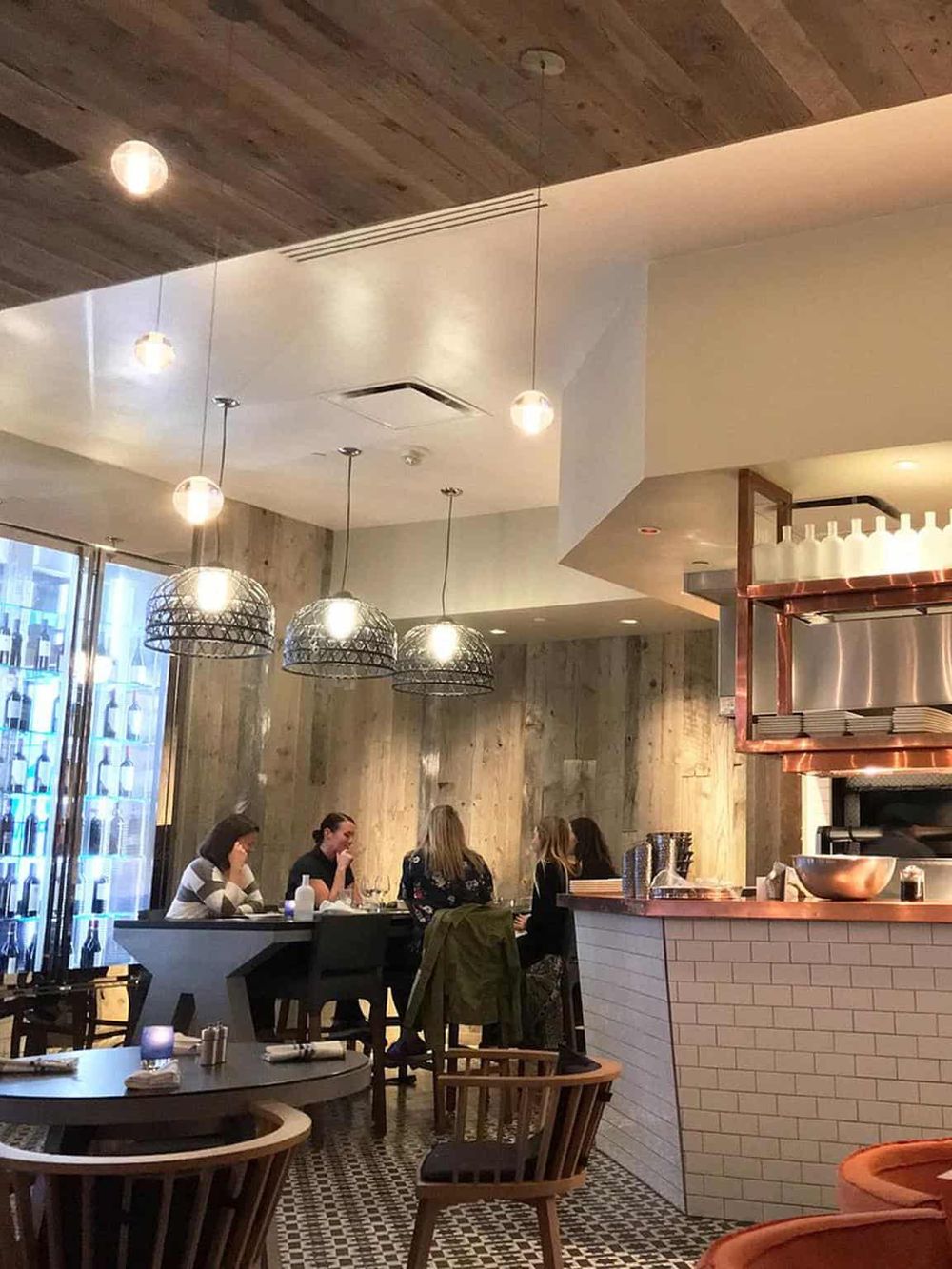 Modern restaurant interior with wooden accents and hanging pendant lights, featuring a cozy dining atmosphere.