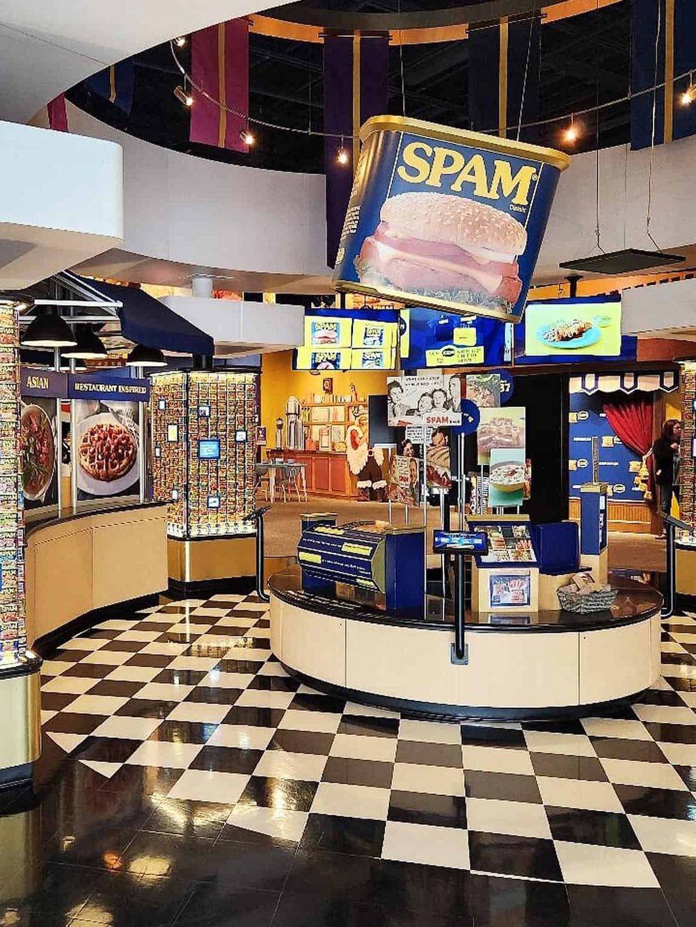 Vibrant food court with SPAM-themed decor, digital menu screens, and checkered flooring at QuestForDirections mall.