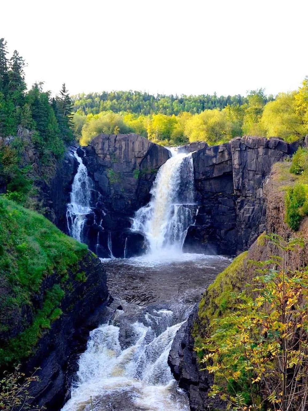 Beautiful waterfall surrounded by lush greenery in a scenic outdoor location.