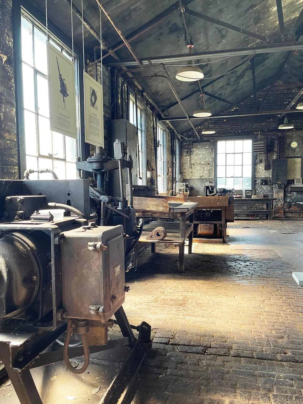 Industrial workshop with vintage machinery and brick flooring, showcasing craftsmanship and historical tools.