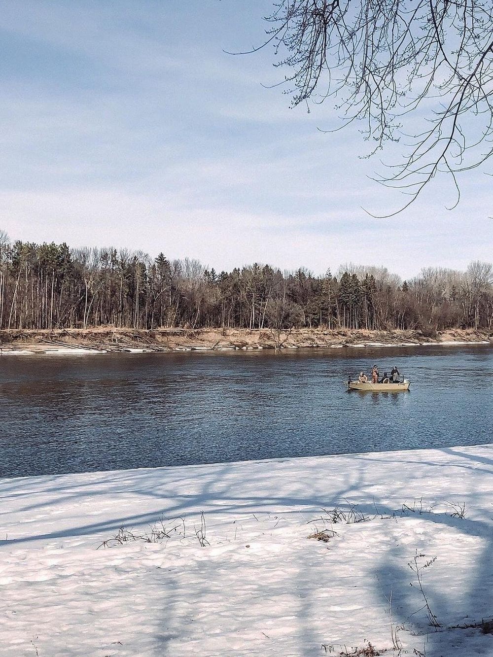 Serene river scene with boat, winter landscape, snow, and trees, perfect for navigation and outdoor adventure planning.