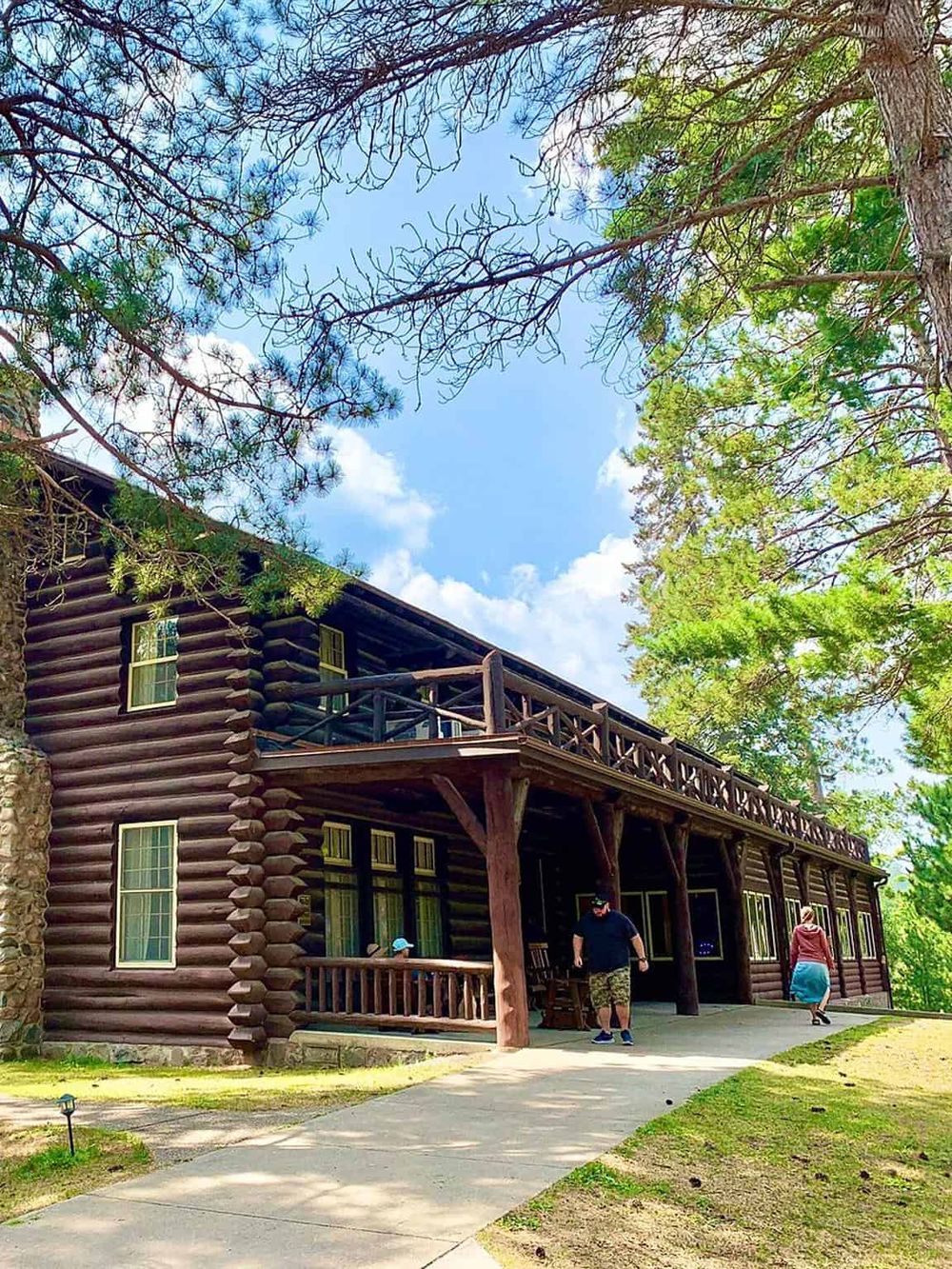 Rustic log cabin with spacious porch nestled among tall trees in nature. Perfect for outdoor adventure and scenic relaxation.