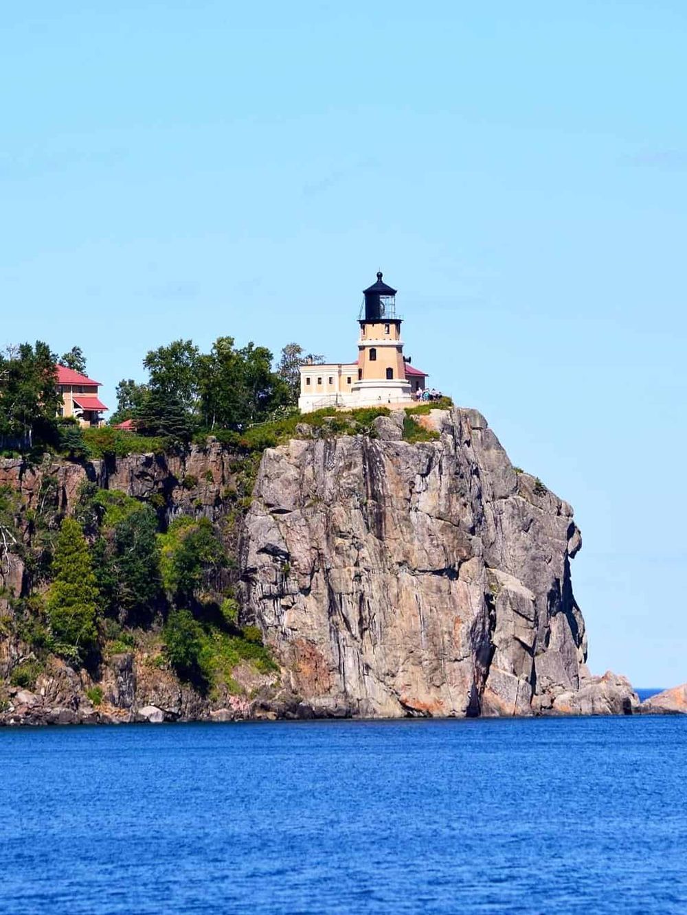 Lighthouse on rocky cliffs overlooking water, scenic coastal navigation landmark, QuestForDirections.