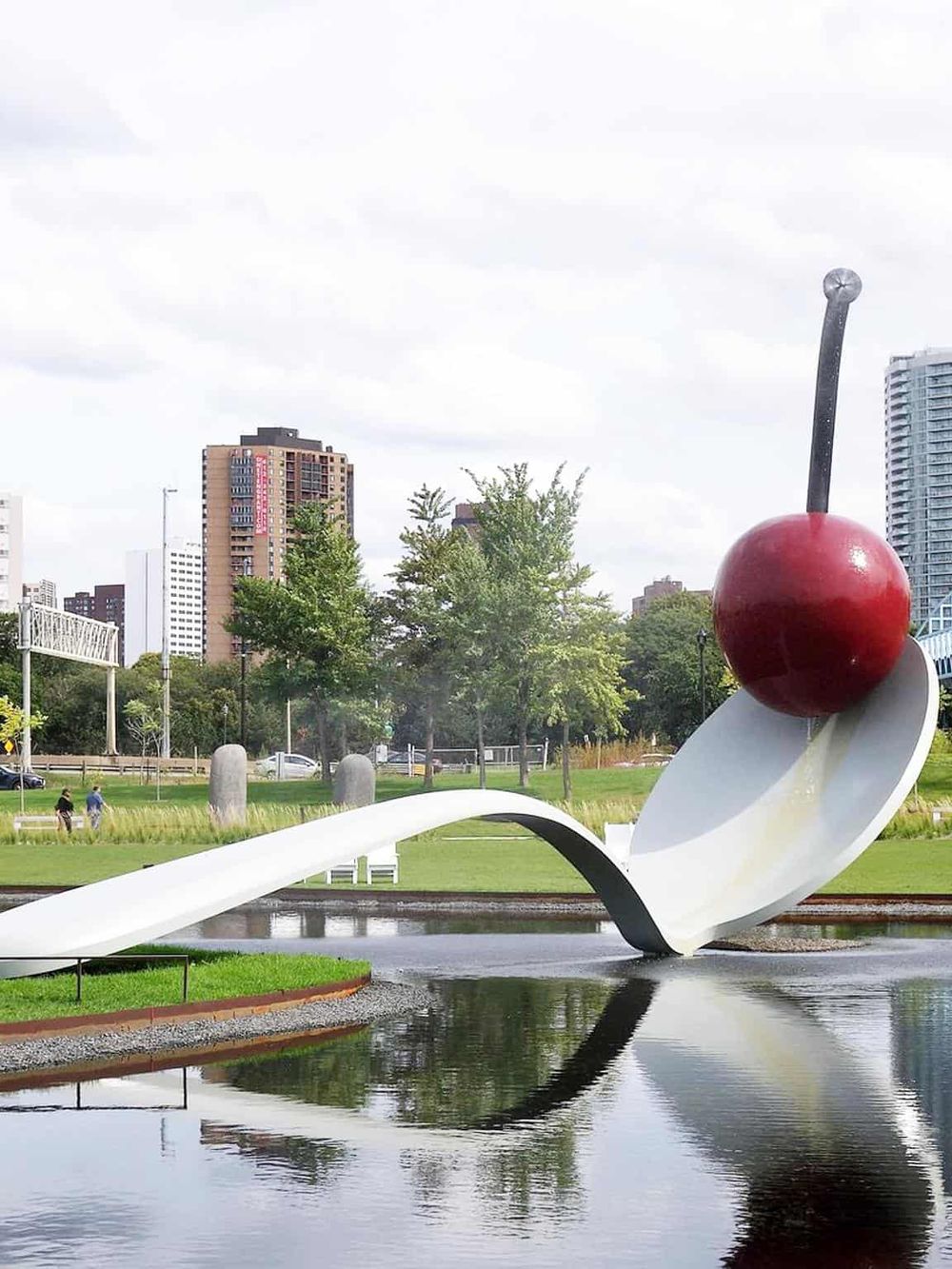 Bright red cherry sculpture at Portland's public park with city skyline backdrop.