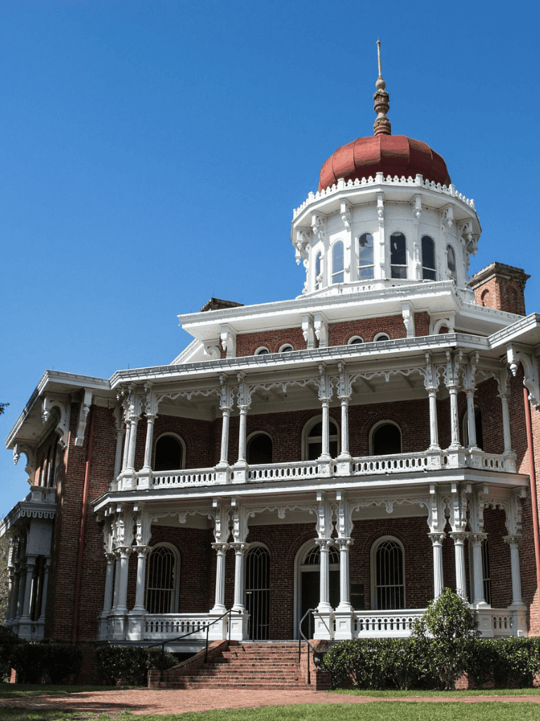 Elegant Victorian-style mansion with ornate white trim and red brick exterior.