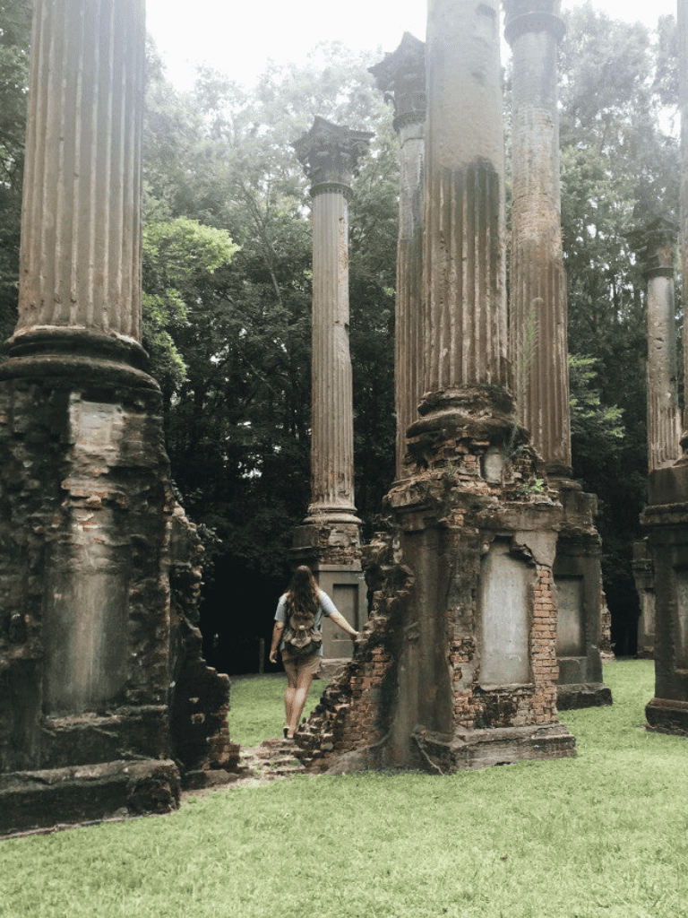 Ancient ruins with tall stone columns in lush green surroundings, historical site exploration.