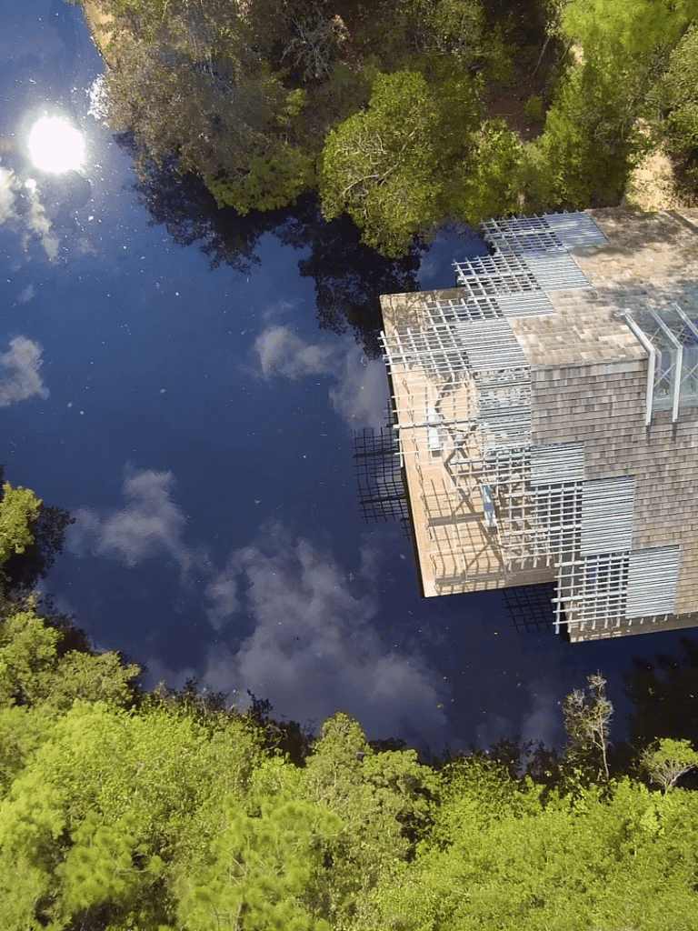 Reflections of blue sky and trees in water near construction site with trees around.