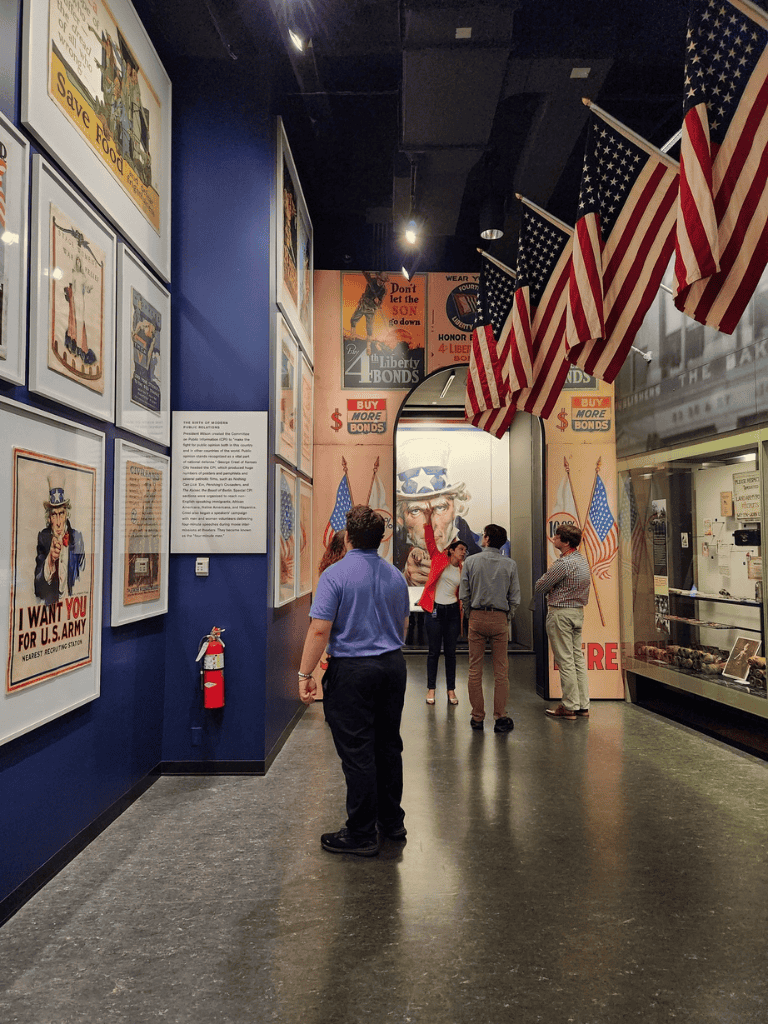 Military history exhibit at QuestForDirections museum, showcasing American patriotic posters and banners.