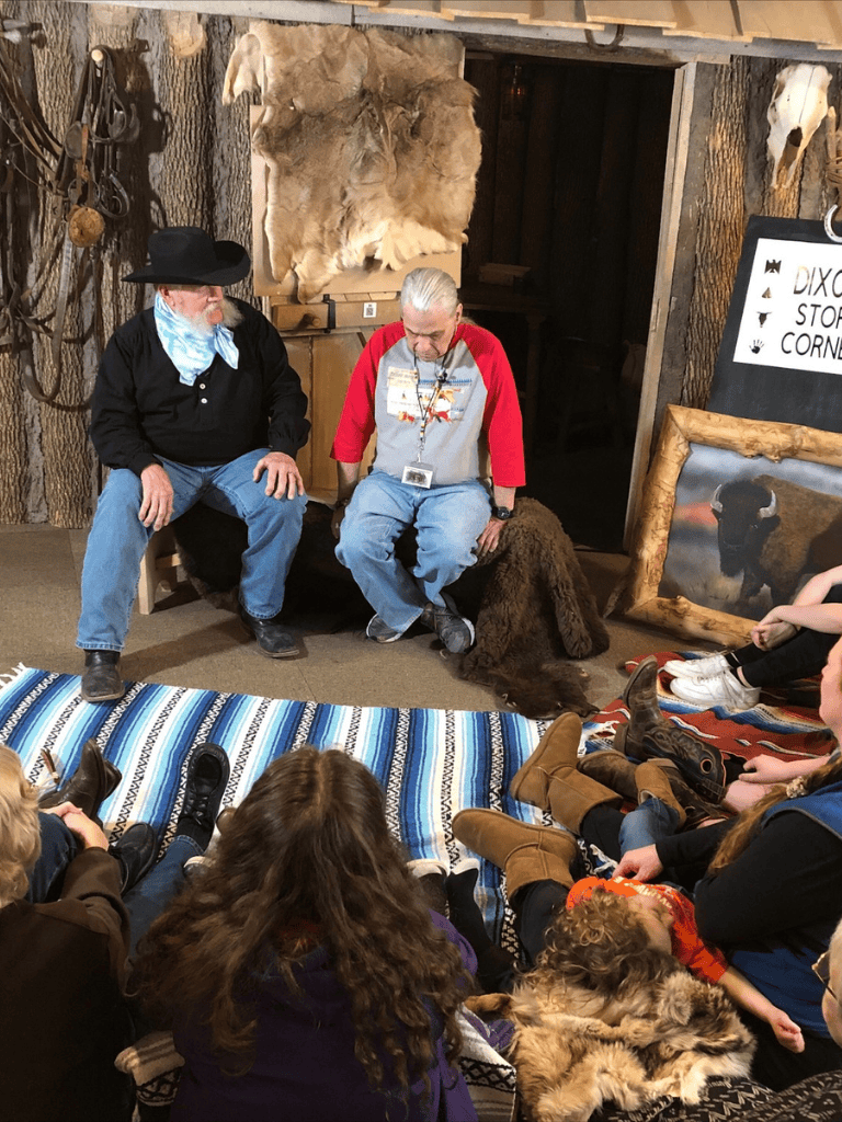 Vintage cowboy demonstration at an indoor wildlife education exhibit, engaging children with authentic Western gear and animal hides.