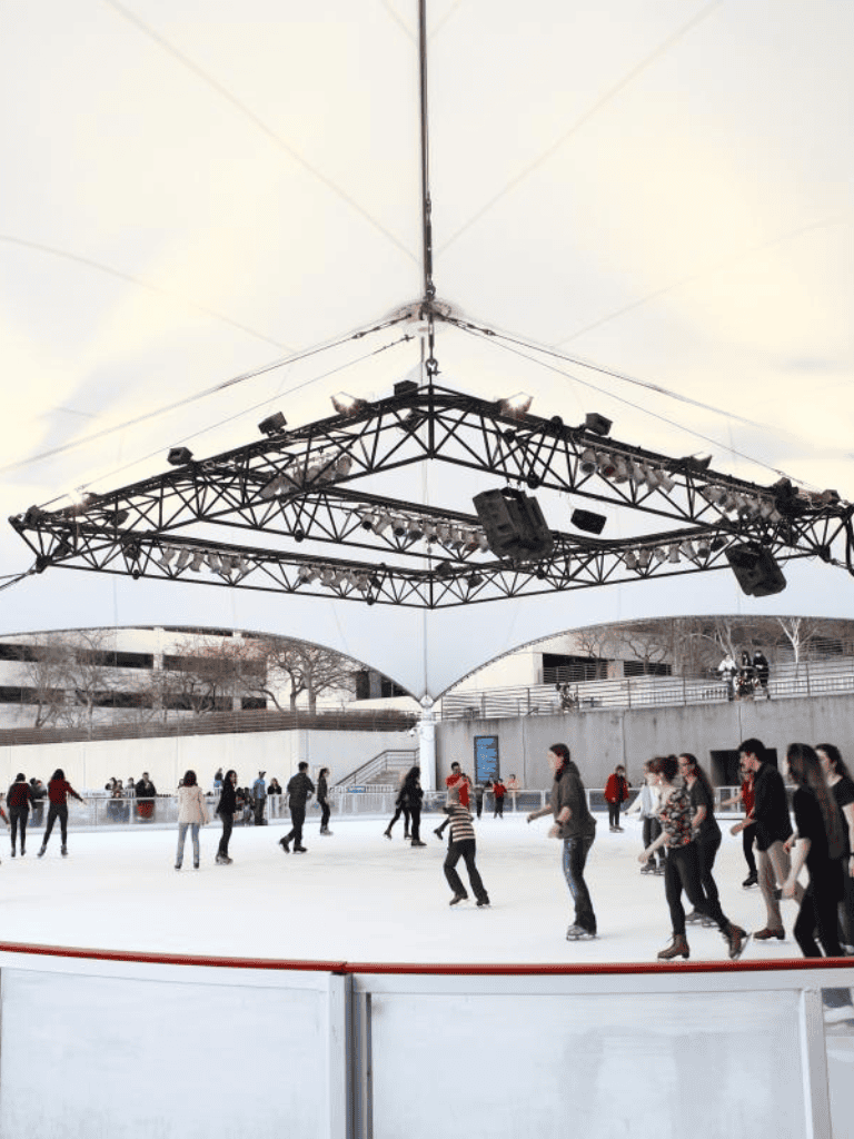 Skating rink with canopy and crowd, outdoor ice skating for fun and recreation.