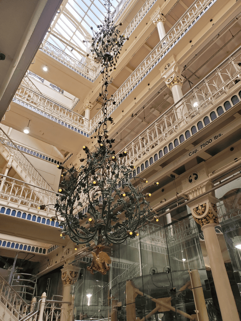 Elegant chandelier inside QuestForDirections shopping mall, featuring ornate architectural details and intricate balustrades.
